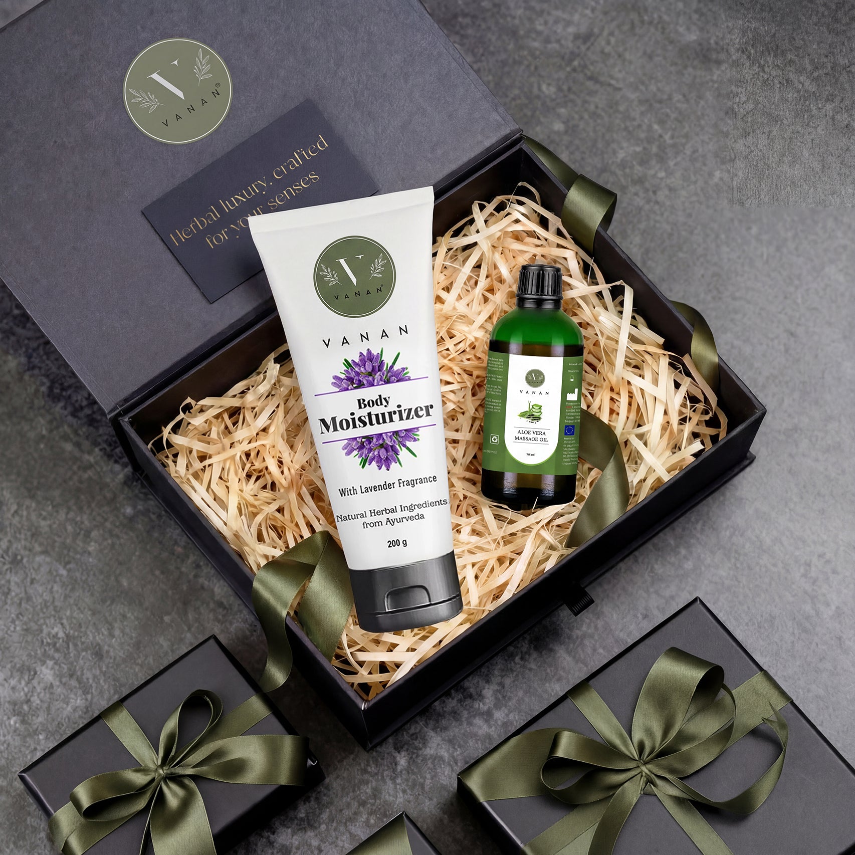 Gift set with Vanan Body Moisturizer and essential oil bottle in a decorative box on a gray surface.